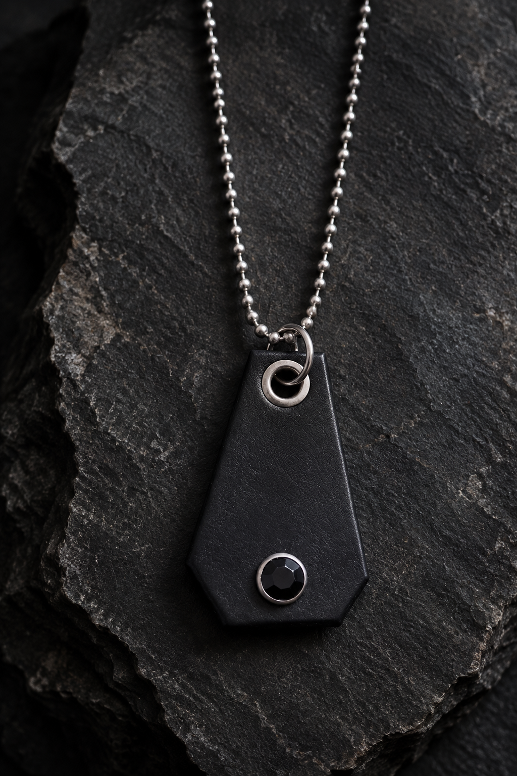 Black leather pendant necklace styled on charcoal stone