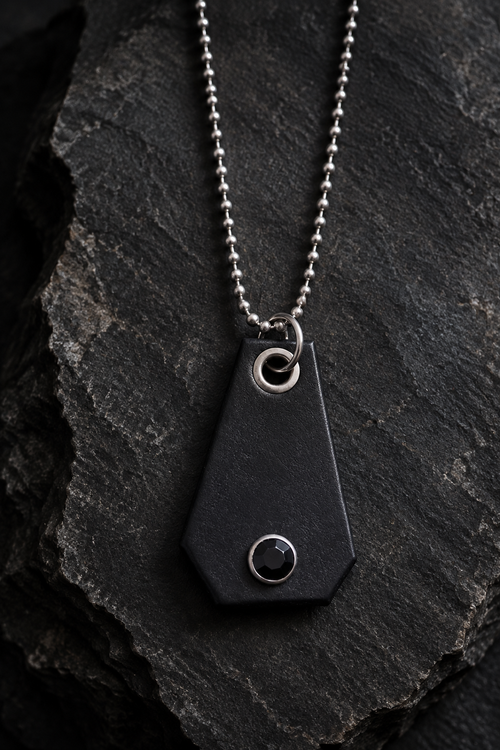 Black leather pendant necklace styled on charcoal stone