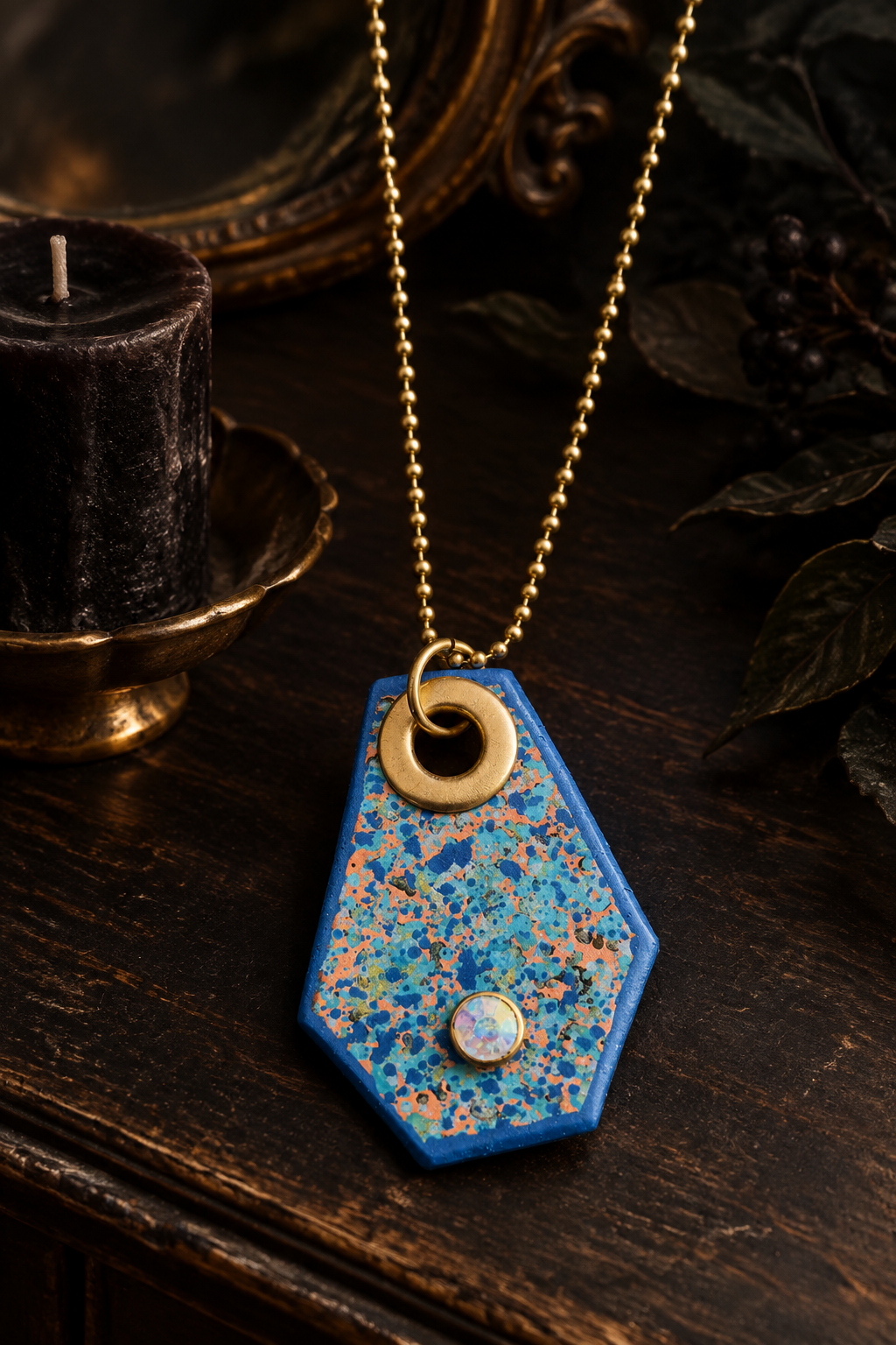 Blue pendant necklace styled on a dark antique vanity