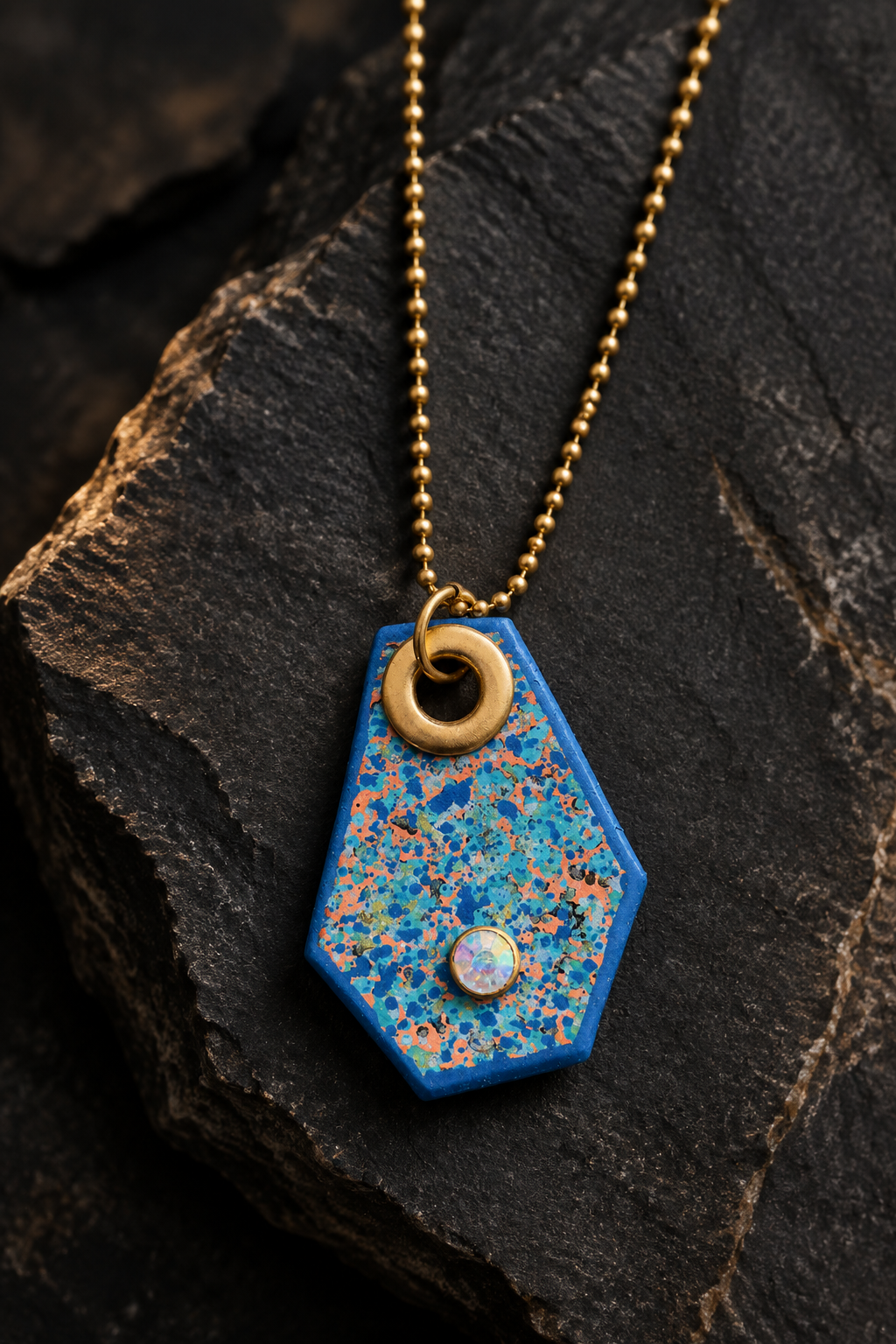 Blue pendant necklace styled on dark charcoal stone